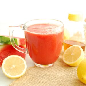 A clear mug filled with soothing hot lemonade with watermelon, cinnamon, and honey.