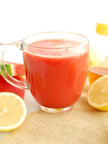 A clear mug filled with soothing hot lemonade with watermelon, cinnamon, and honey.