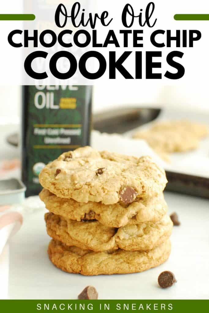 A stack of olive oil chocolate chip cookies next to a bottle of olive oil and some scattered chocolate chips.