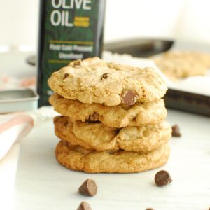 Several olive oil chocolate chip cookies stacked on top of each other.