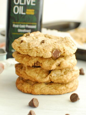 Several olive oil chocolate chip cookies stacked on top of each other.