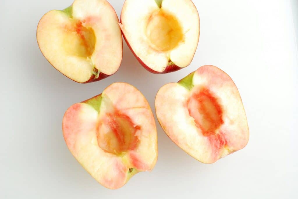 Apples that have been cut in half on a cutting board.