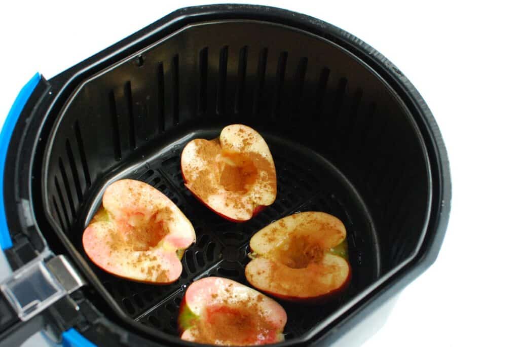 Apples in the basket of an air fryer before cooking.