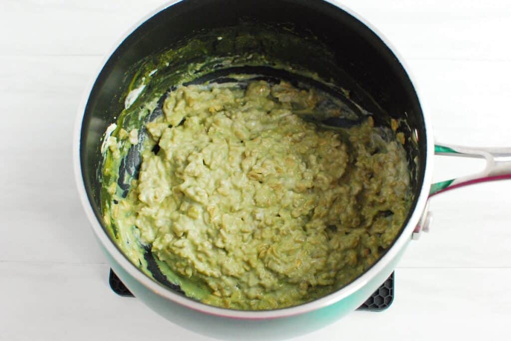 Yogurt and honey stirred into matcha oatmeal in a pot.