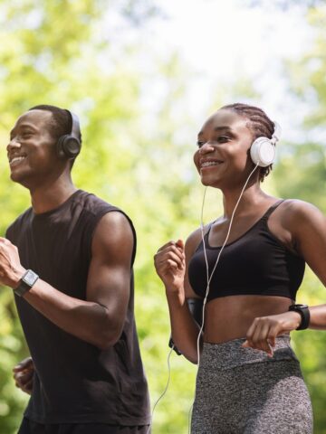 Two runners outside with headphones on listening to a podcast.