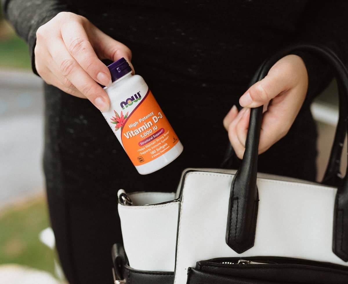 A woman taking a bottle of Vitamin D out of her purse.