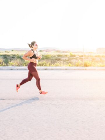 An athletic woman running outside on a sunny day.