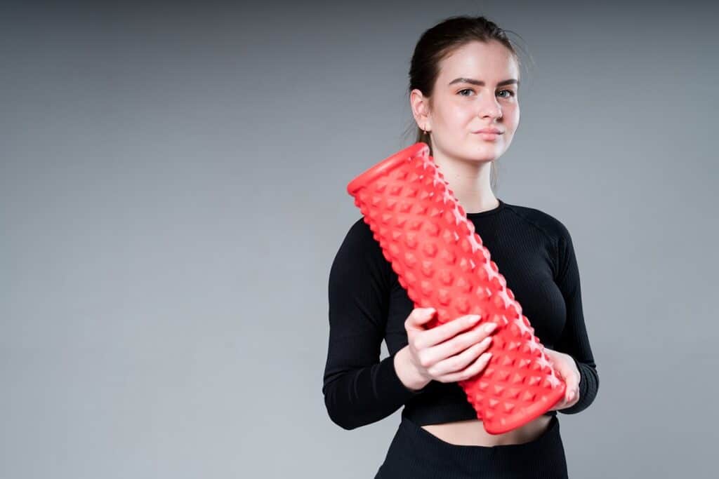 A woman holding a red foam roller.
