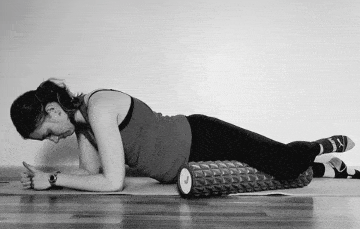 A woman foam rolling her inner thigh.