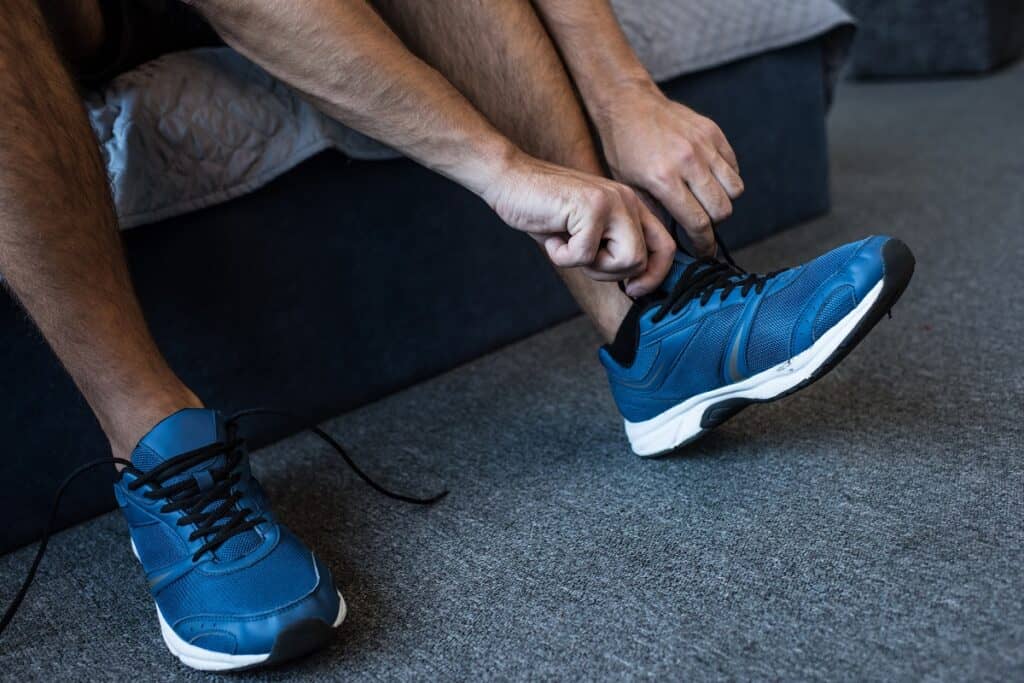 A runner putting on a pair of memory foam sneakers.