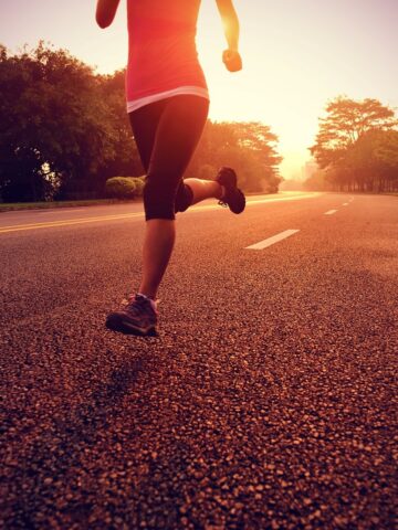 A woman running outside on the road on a sunny evening.
