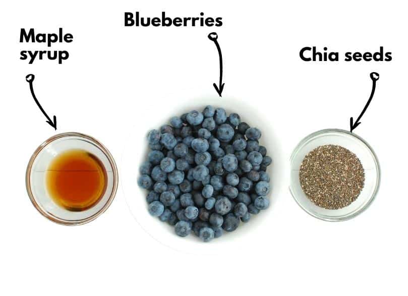 A bowl of blueberries, a small bowl with maple syrup, and a small bowl with chia seeds.
