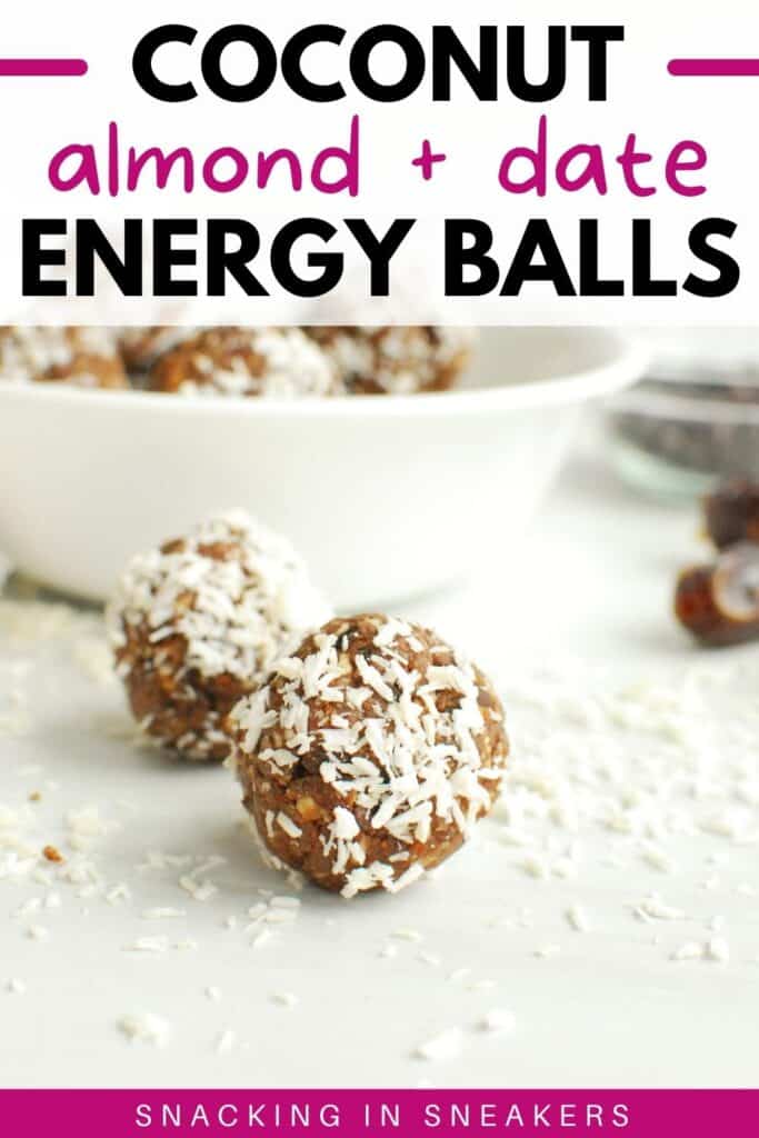 Two coconut almond date balls on a white table with a bowl in the background.