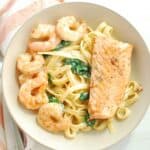 A bowl of shrimp and salmon pasta next to a napkin.