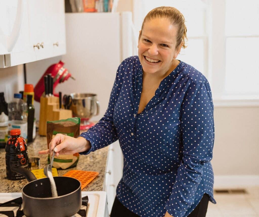 A woman adding gelatin to a pot.