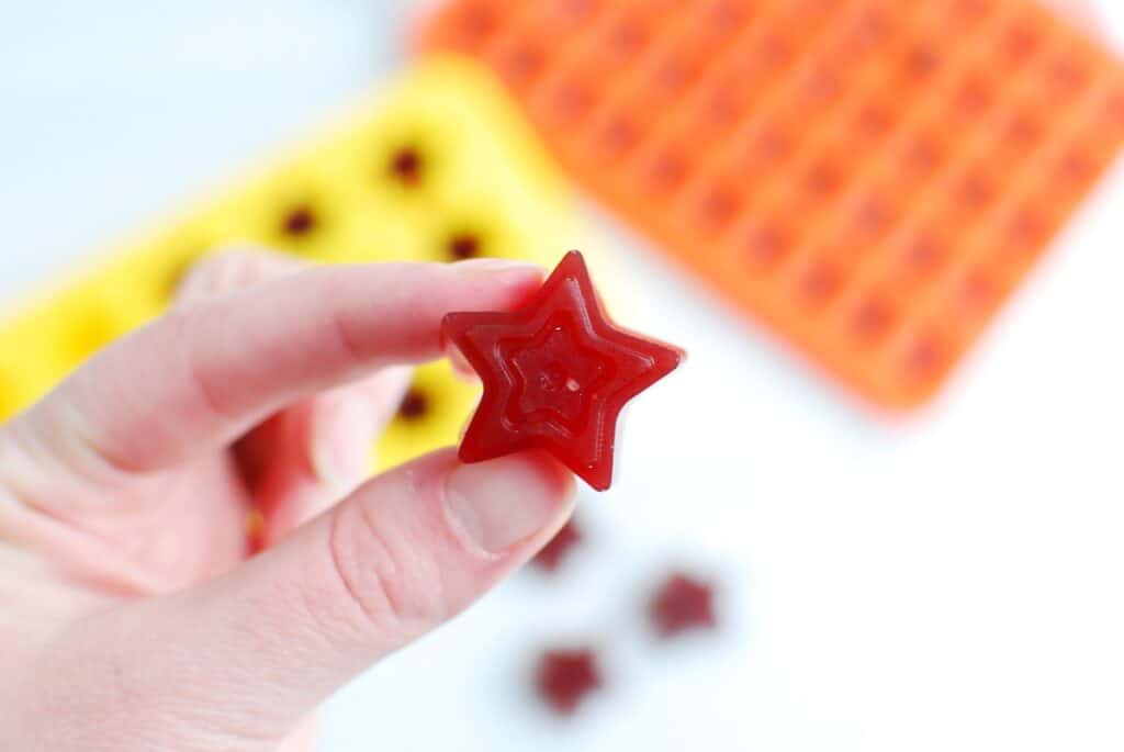 A woman holding a star-shaped tart cherry gummy.