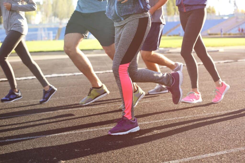 Legs of people who are running on the track.