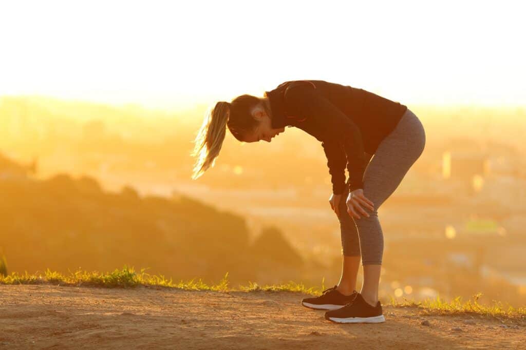 A woman that's feeling tired and sore at the end of a run, wondering if lactic acid contributed.