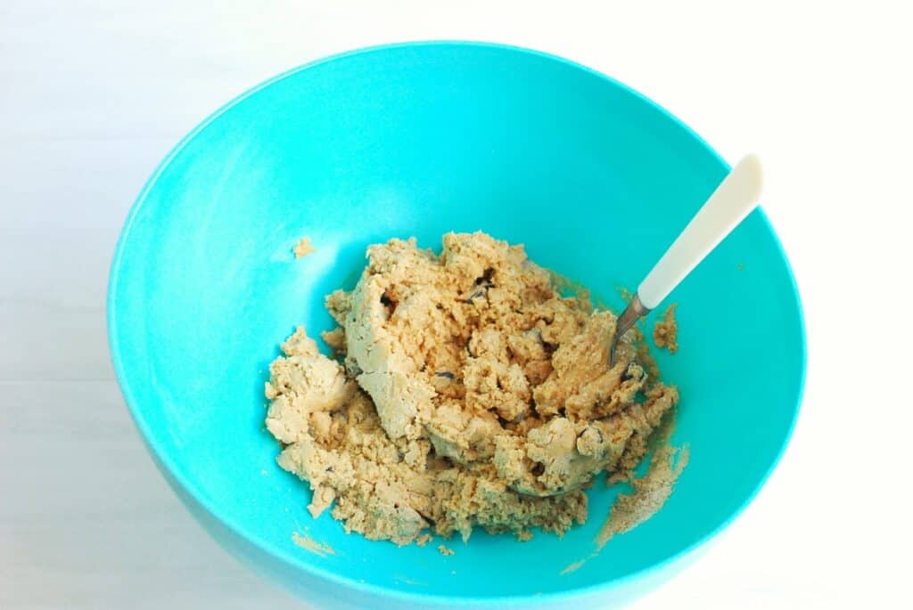 A bowl with a mixture of peanut butter, protein powder, honey, and chocolate chips.