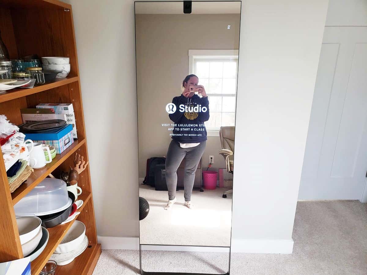 A woman standing in front of a lululemon studio mirror.