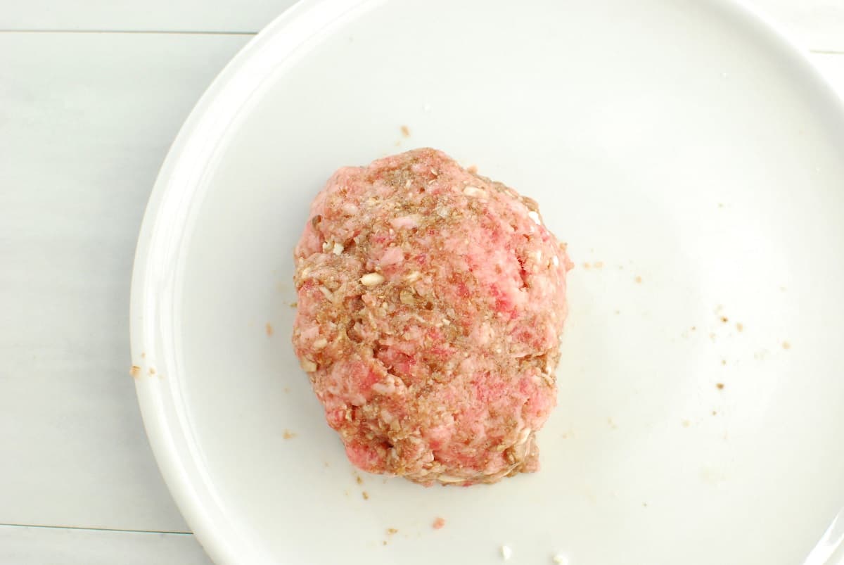 A fully assembled feta stuffed burger patty that is uncooked.