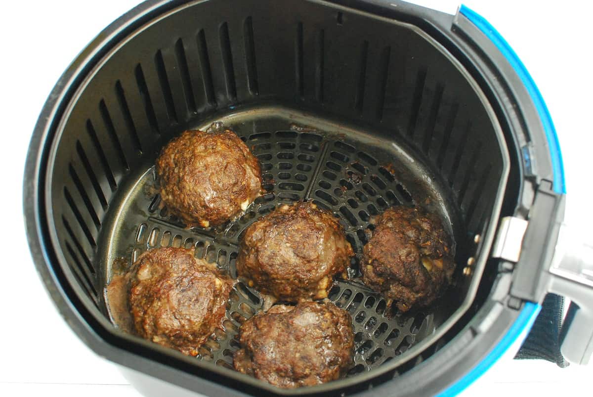 Cooked lamb burgers in the air fryer basket.