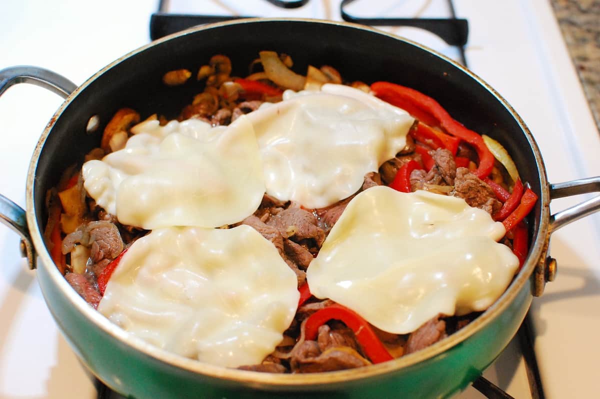 Provolone cheese melting on top of the cheesesteak mixture.