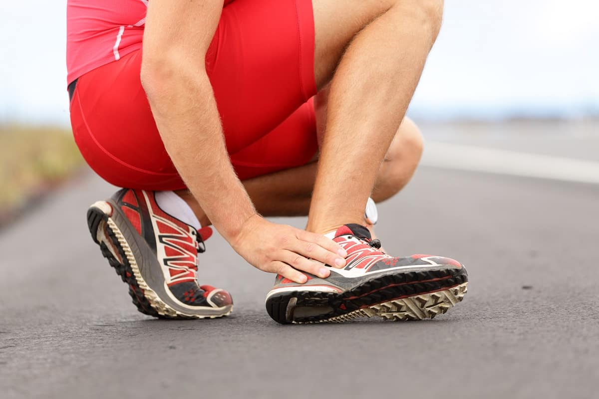 A runner holding the back of their foot.