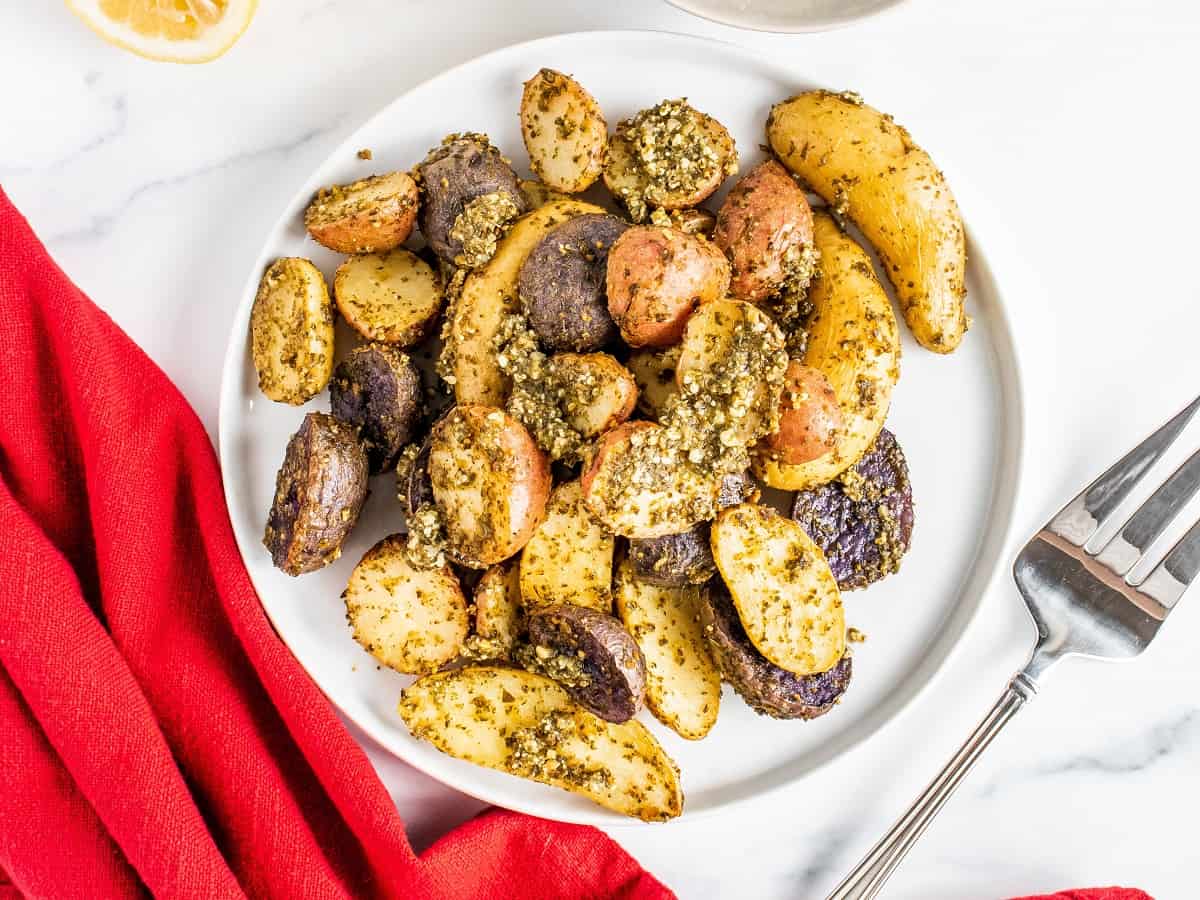 Roasted pesto potatoes on a white plate, next to a red napkin.