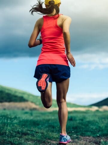 A woman running outside near mountains on a cloudy day.