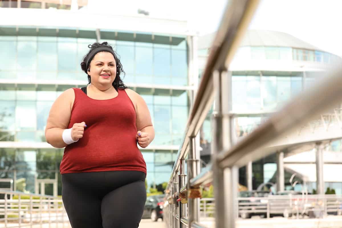 A curvy woman running outside near a building.