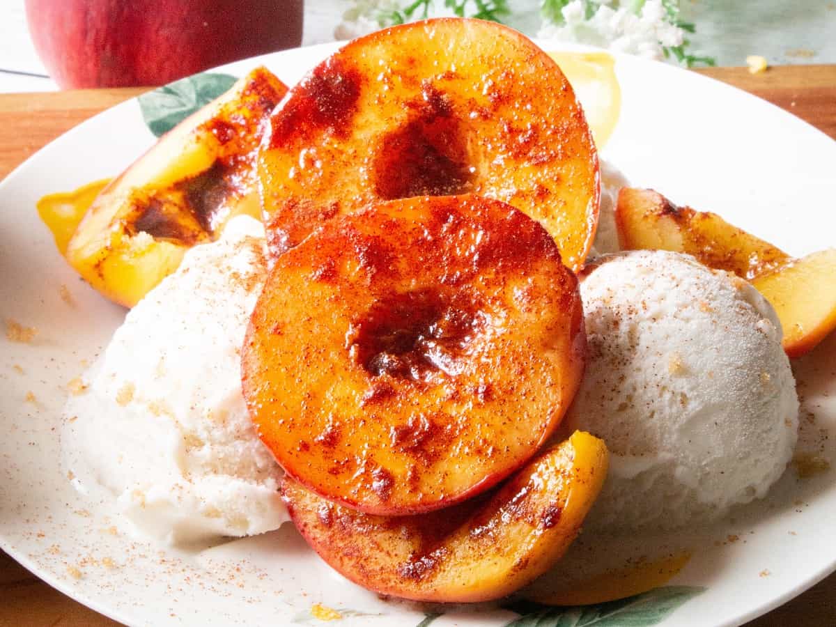 A plate with air fryer caramelized peaches and ice cream.