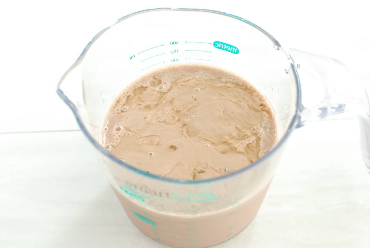 Chocolate milk mixed with lemon juice in a measuring cup.