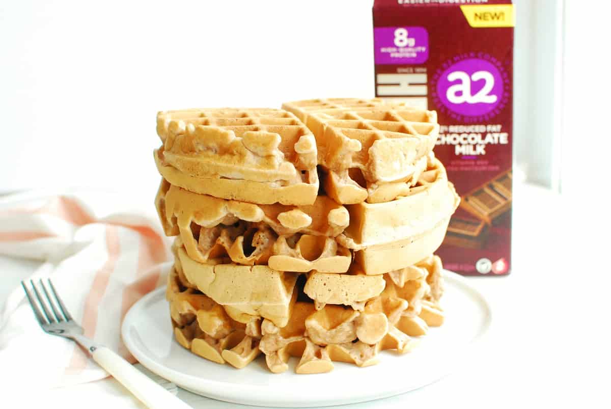 A stack of three chocolate milk waffles on a plate.