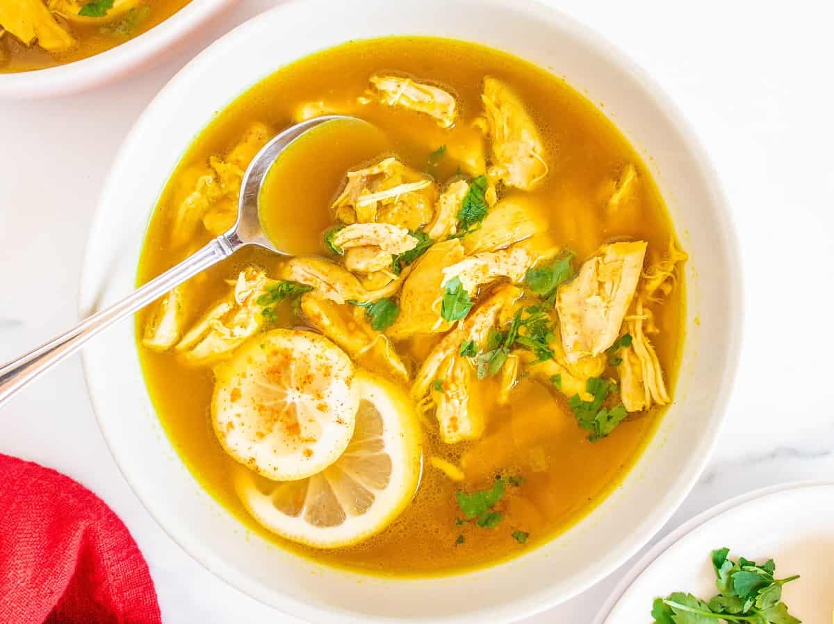 A bowl of ginger lemon chicken soup garnished with parsley.