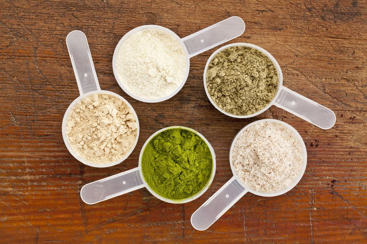 Several different types of protein powder for runners in scoops.