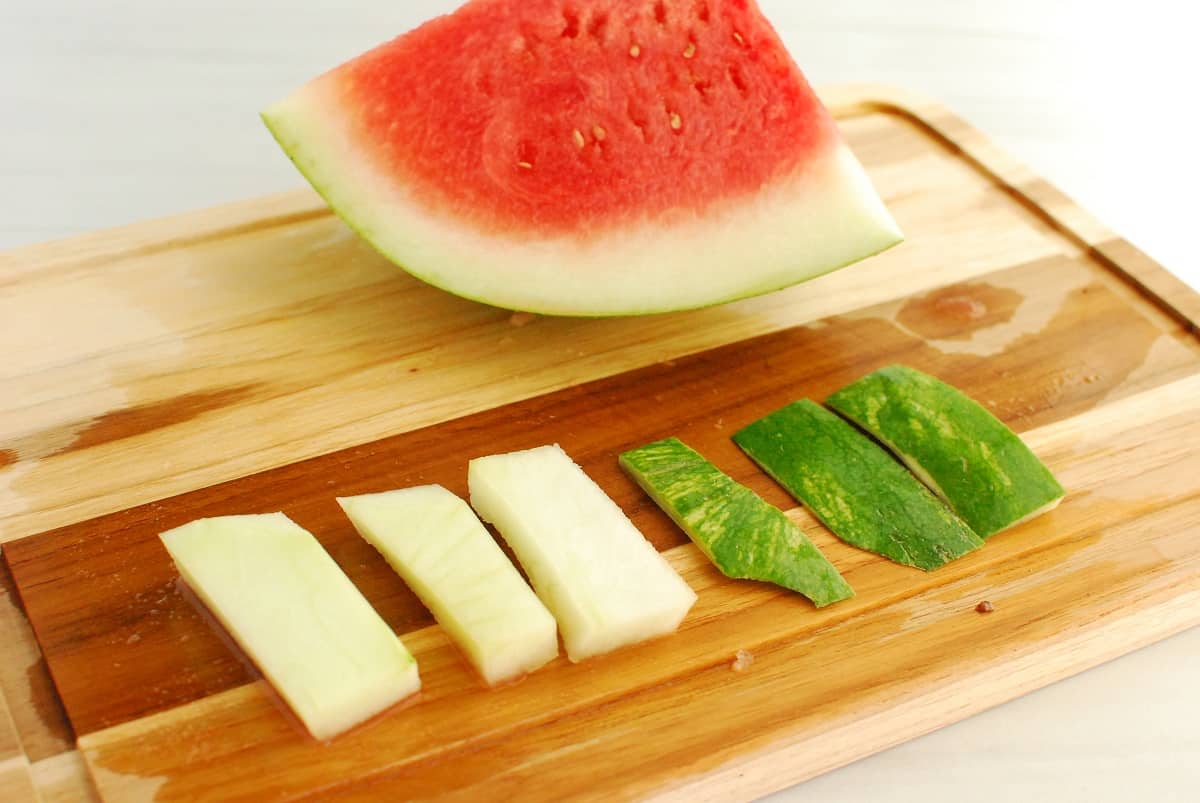 Watermelon on a cutting board with the rind and peel separated.