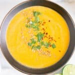 A bowl of frozen butternut squash soup garnished with cilantro and pumpkin seeds.