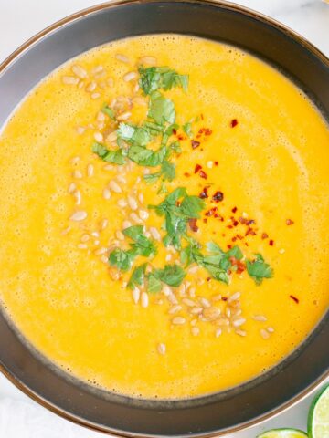 A bowl of frozen butternut squash soup garnished with cilantro and pumpkin seeds.