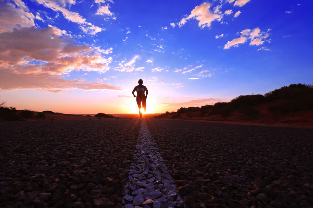 A person running outside on the road at sunset.