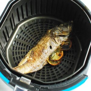 A whole fish cooked in the air fryer basket.