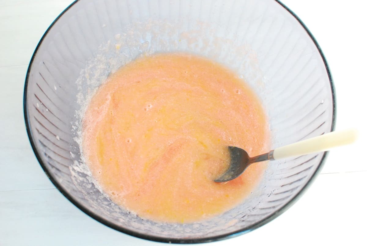 Watermelon puree mixed together with egg, oil, sugar, and vanilla in a bowl.