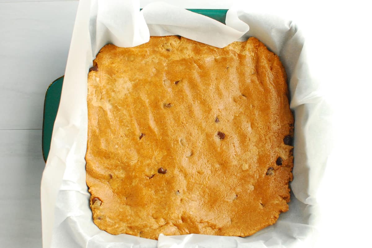 Protein bar mixture pressed into a parchment-lined 8 by 8 baking dish.