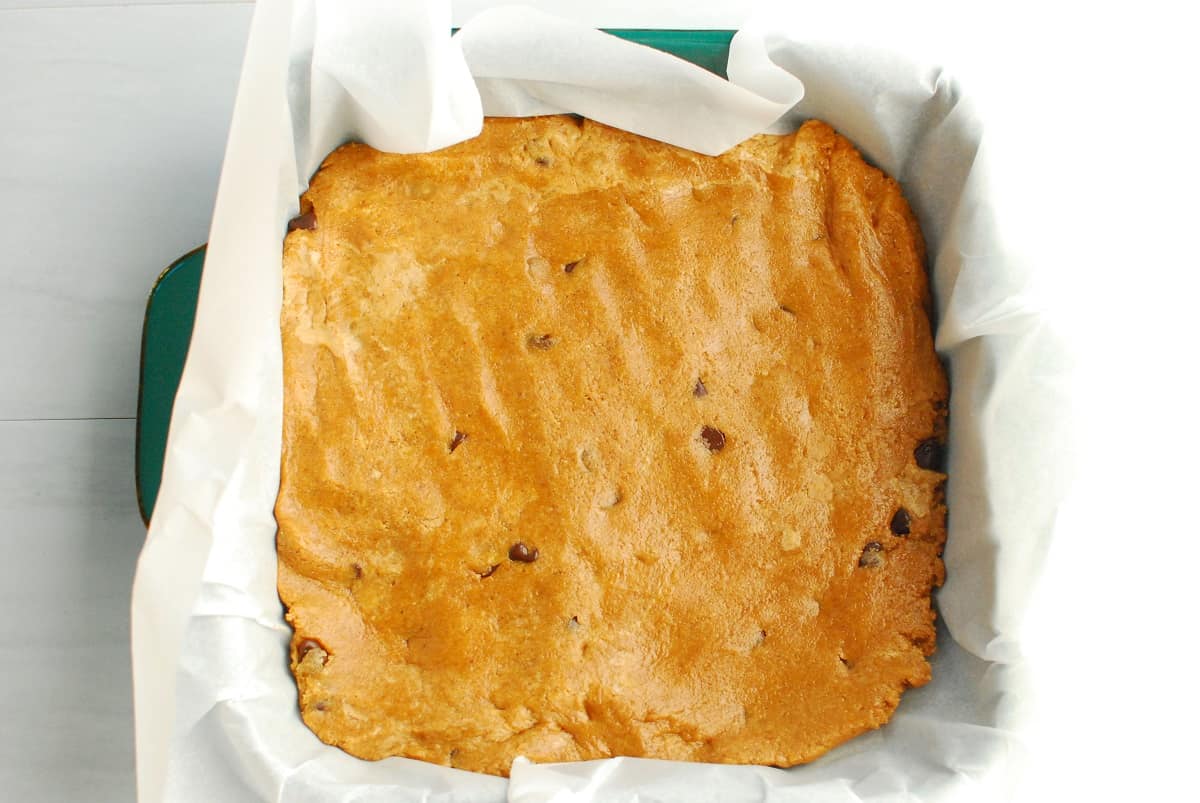 Protein bar mixture pressed into a parchment-lined 8 by 8 baking dish.