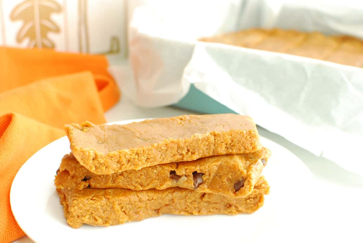 Several pumpkin protein bars on a plate next to an orange napkin and a baking dish.