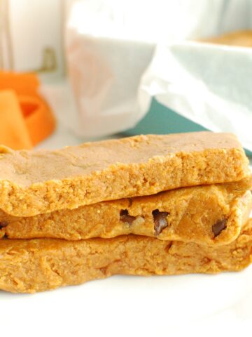 Three pumpkin protein bars stacked on top of each other on a white plate.