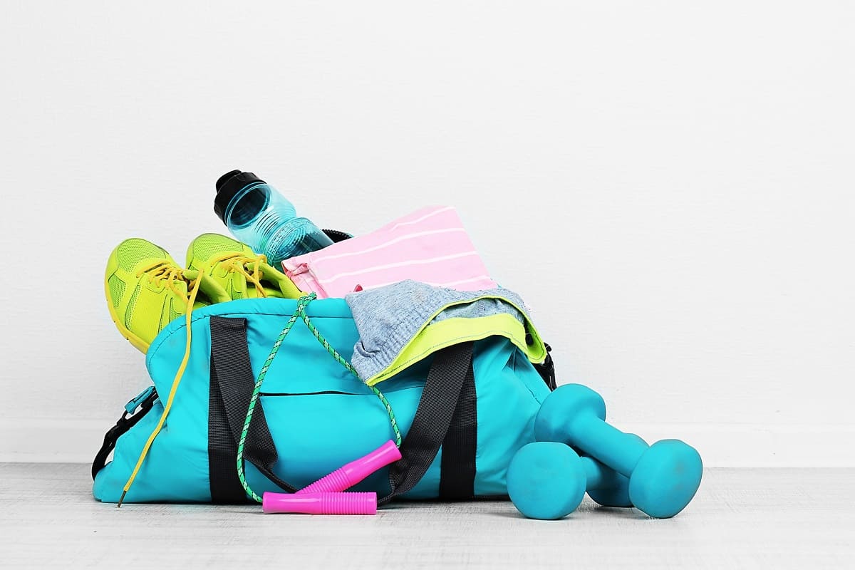 A gym bag with dumbbells, a water bottle, and other fitness gear.