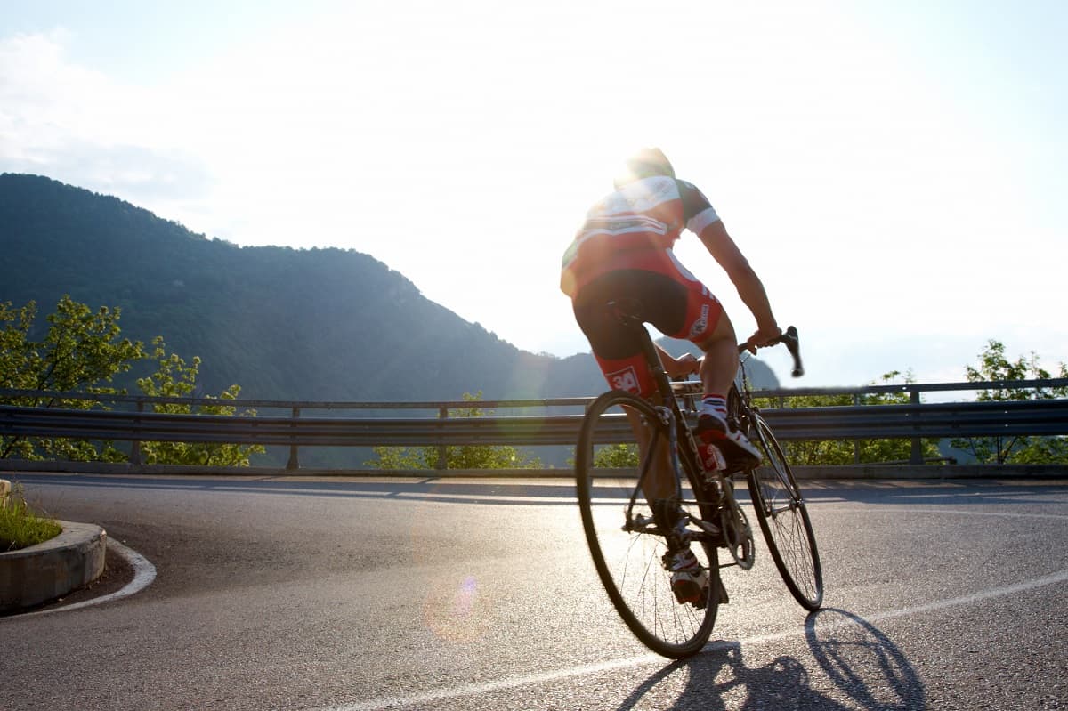 A cyclist riding on a bright day on the road.