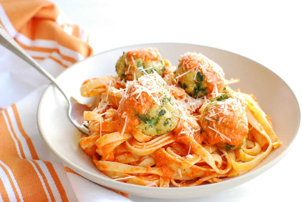 Chicken meatballs on top of roasted red pepper pasta.