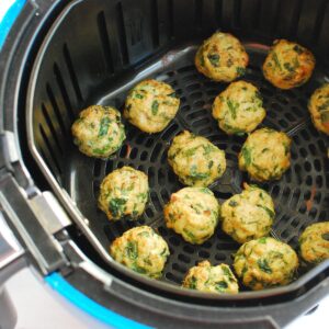 Air fryer chicken meatballs in the air fryer basket after cooking.